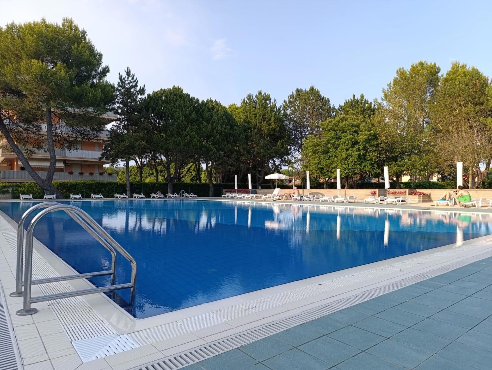 A swimming pool with lounge chairs and a building in the background.