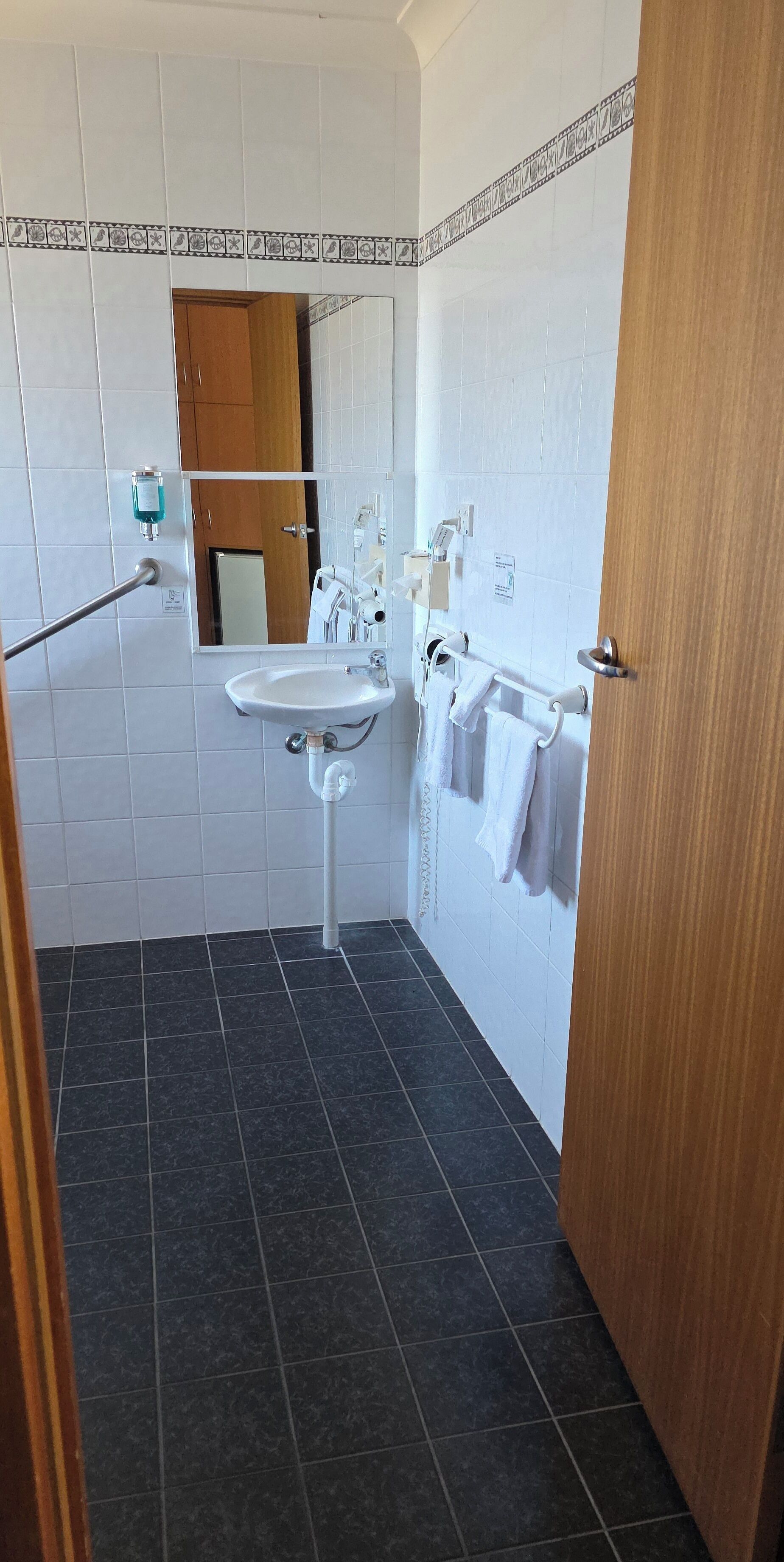 A bathroom with a white sink, mirror, and towel rack.
