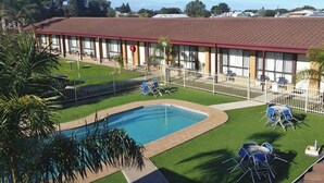 A hotel with a swimming pool, outdoor seating, and a fenced patio area. - Kingston Ocean View Motel (Kingston SE)