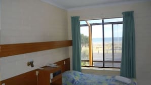A room with two beds, a wooden headboard, a window with curtains, and a view of the beach. - Kingston Ocean View Motel (Kingston SE)