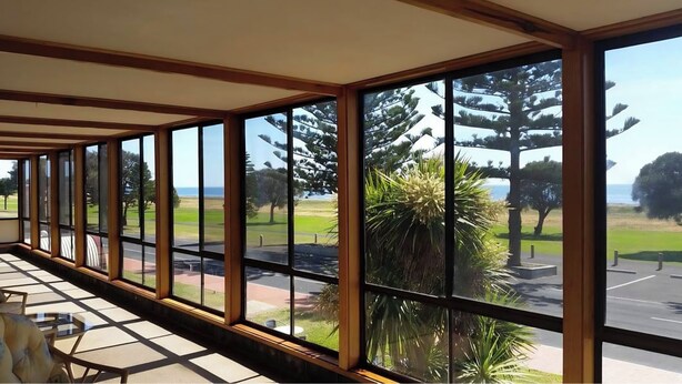 A conservatory with large windows offering views of a park and the sea. - Kingston Ocean View Motel (Kingston SE)