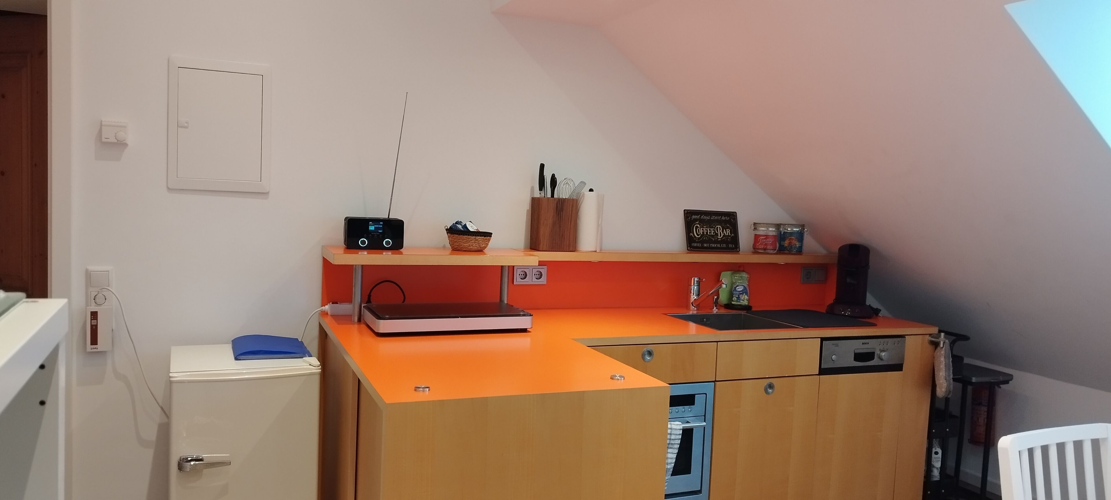 Een compacte keuken met een ingebouwde oven, een koffieapparaat en een radio.