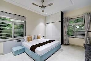 A bedroom with a bed, a ceiling fan, and a window with blinds.