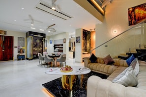 A modern living room with a marble coffee table, a sofa with cushions, and a dining area with chairs and a table.