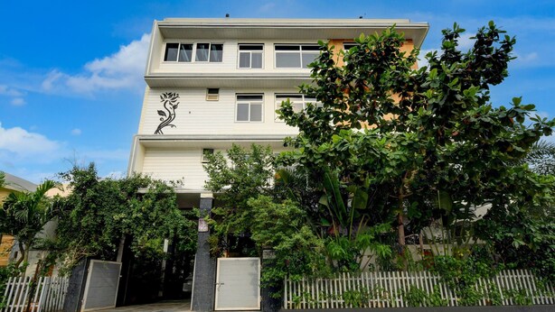 A two-story building with a white facade, a decorative black floral design on the lower facade, and a gated entrance. - Villa Verizon by Dancenter (Hyderabad)