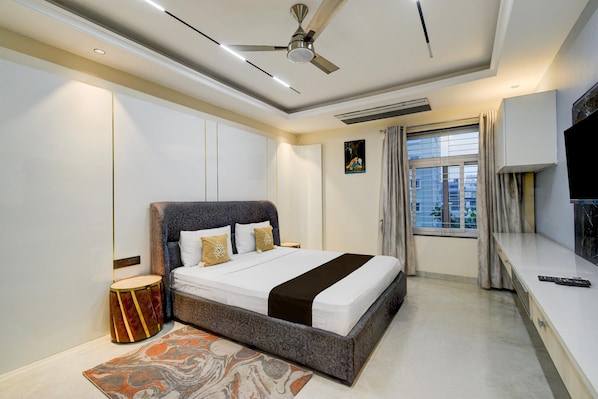 A modern hotel room with a large bed, a television, and a window with curtains.