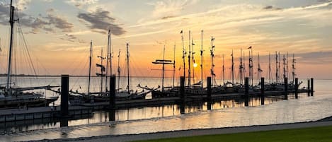 A marina with multiple boats docked at wooden piers during sunset.