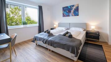 Una camera da letto moderna con un letto, comodini, una scrivania e una sedia.
