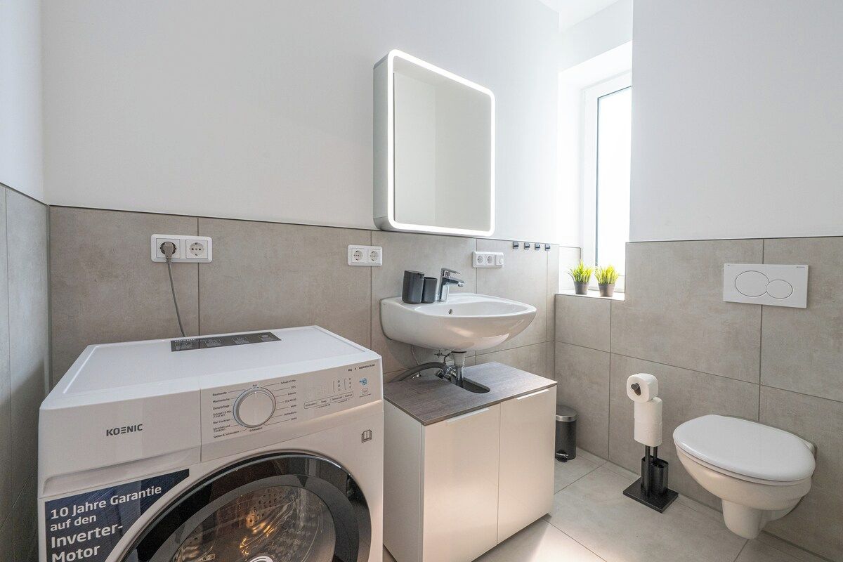 Ein modernes Badezimmer mit Waschmaschine, Waschbecken und Toilette.