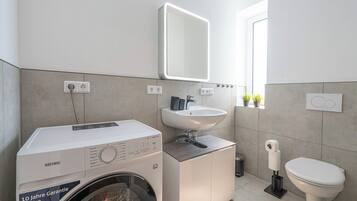 Ein modernes Badezimmer mit Waschmaschine, Waschbecken und Toilette.