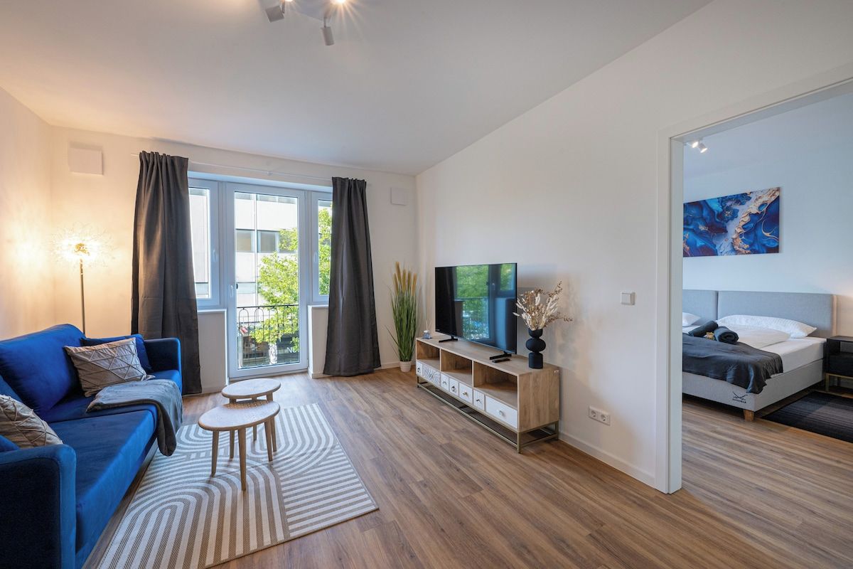 Ein modernes Wohnzimmer mit einer Couch, einem Fernseher, einem kleinen Tisch und einem Bett.