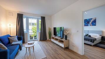 Ein modernes Wohnzimmer mit einer Couch, einem Fernseher, einem kleinen Tisch und einem Bett.