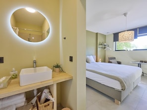 Un bagno moderno con uno specchio rotondo, un lavandino bianco e una pianta in vaso.