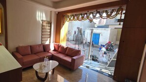 A living room with a sectional sofa, a coffee table, and a framed picture on the wall. - HOTEL HANIE TREE (Dwarka)