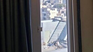 A window with a view of a cityscape, including buildings and a crane. - HOTEL HANIE TREE (Dwarka)