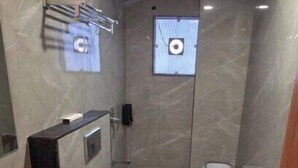 A bathroom with a marble floor, a sink, a toilet, and a shower area. - HOTEL HANIE TREE (Dwarka)