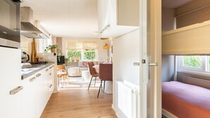Eine moderne Küche mit weißen Schränken, einem eingebauten Backofen und einem Essbereich mit Tisch und Stühlen.