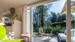 Eine moderne Küche mit großem Fenster, einem Essbereich mit Tisch und Stühlen sowie Blick auf den Garten.