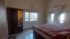 A bedroom with a bed, a door, and two windows.