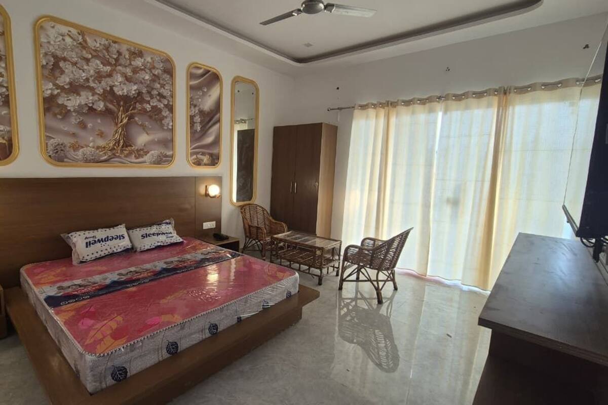 A bedroom with a large bed, a desk, and a chair. There are wall-mounted mirrors and a ceiling fan.