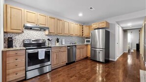 A modern kitchen with wooden cabinets, stainless steel appliances, and a tiled backsplash. - Peaceful 2-bedroom apartment - Walk Everywhere (Philadelphia)