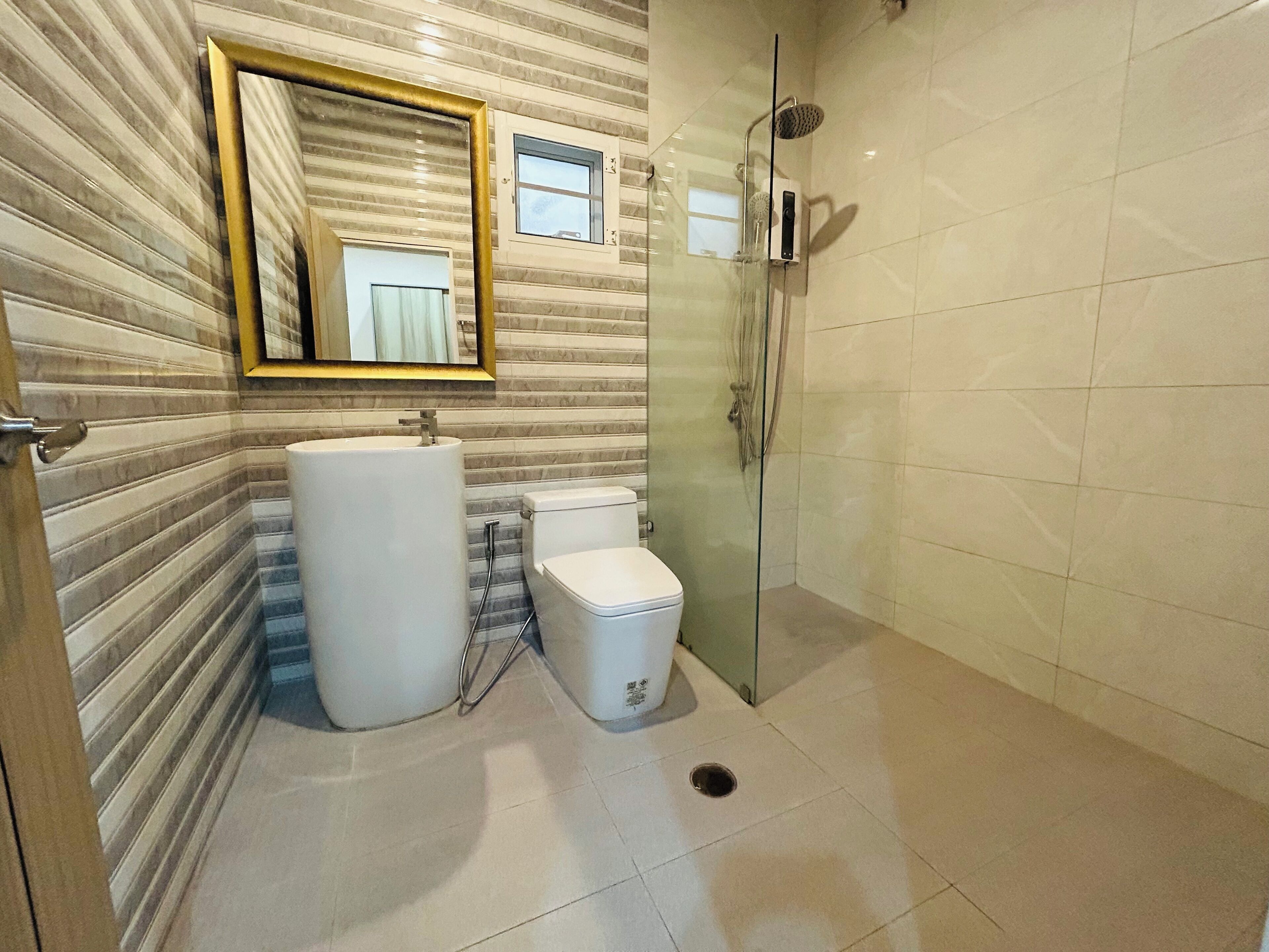 Ein Badezimmer mit großem Spiegel, Toilette, Waschbecken und Dusche.