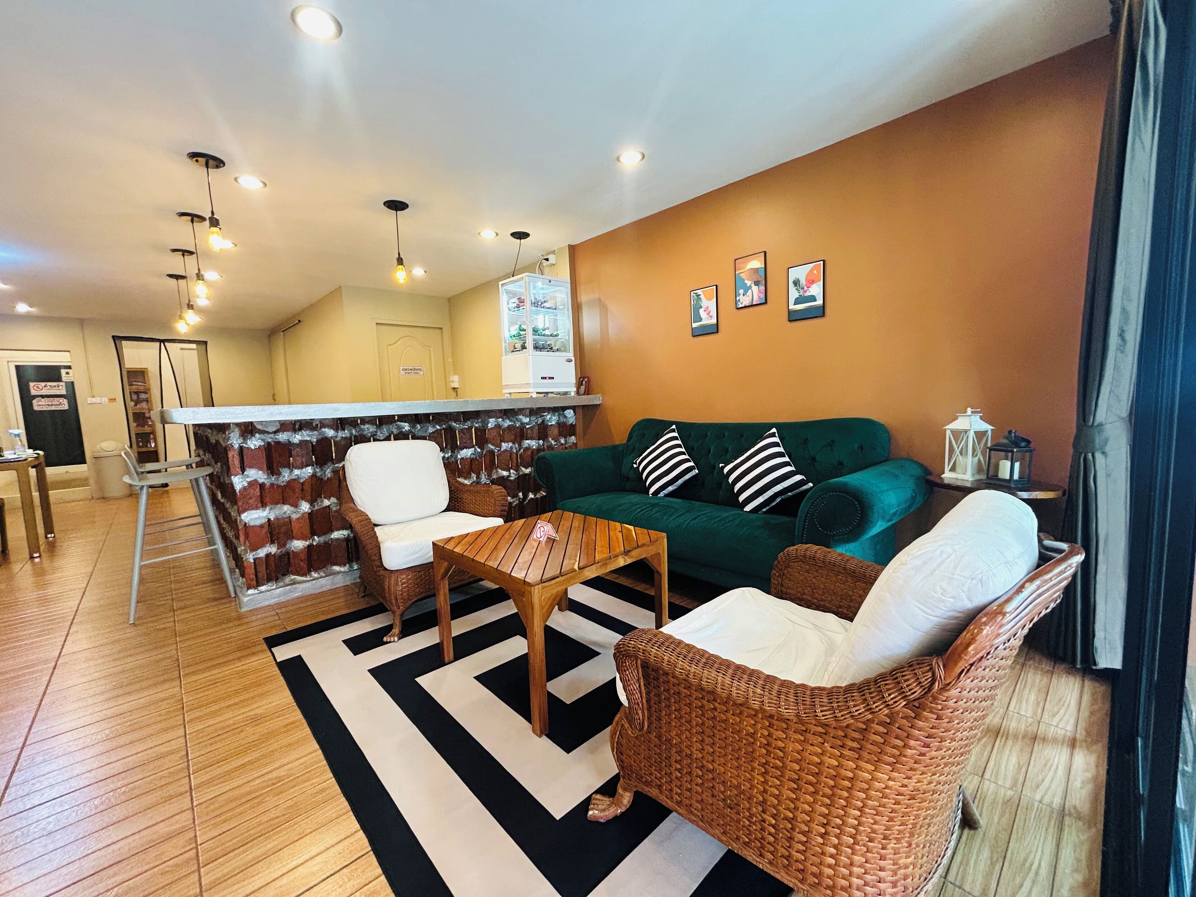 A living room with a green sofa, wicker chairs, a wooden coffee table, and a black-and-white striped rug.