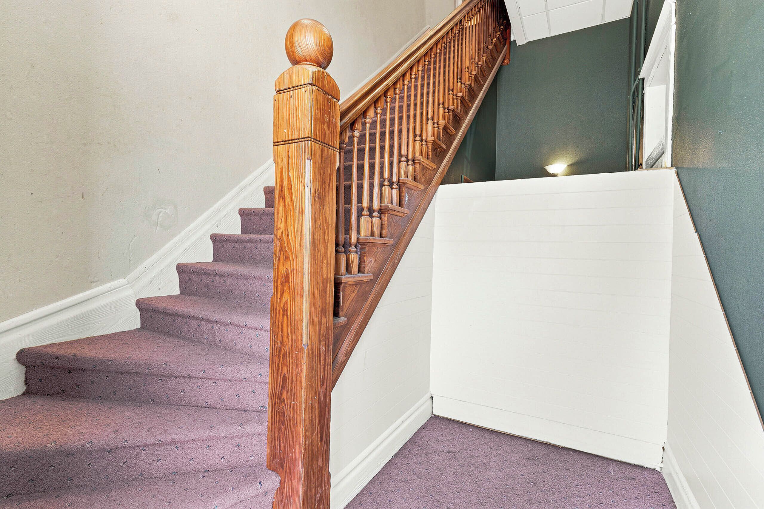 A wooden staircase with a handrail leading to a landing.