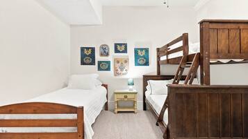 A bedroom with two wooden bunk beds, a small bedside table with a lamp, and several decorative wall pieces.