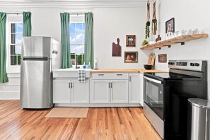 A modern kitchen with white cabinets, stainless steel appliances, and a wooden countertop.