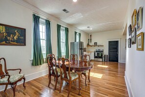 A dining area with a wooden table and chairs, a painting on the wall, and a kitchen in the background. - Historic Apartment in Chapman! Walkable Getaway (Chapman)