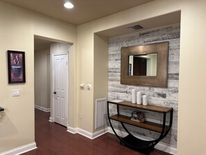 A hallway with a white door, a framed picture, a mirror, and a console table with books. - 2-bedroom condo in adorable Los Angeles with AC for your stay near the beaches (Los Angeles)