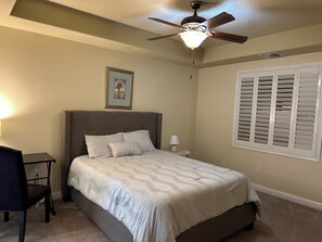 A bedroom with a bed, a desk, a chair, a ceiling fan, and a window with shutters. - 2-bedroom condo in adorable Los Angeles with AC for your stay near the beaches (Los Angeles)