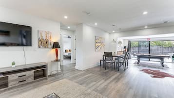 A modern living room with a flat-screen TV, a pool table, and a dining area.