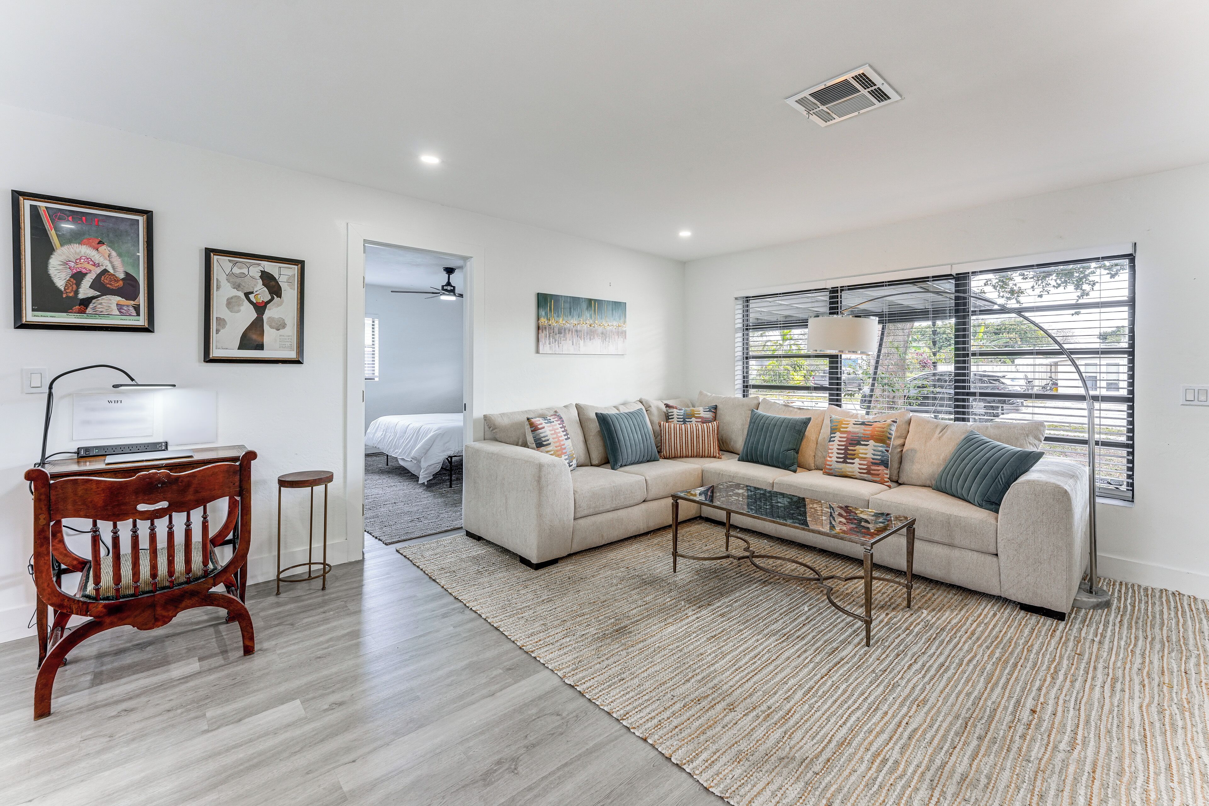 A modern living room with a sectional sofa, a wooden bench, a glass coffee table, and artwork on the walls.
