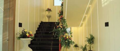 A modern staircase with a dark finish, flanked by decorative vases and potted plants.