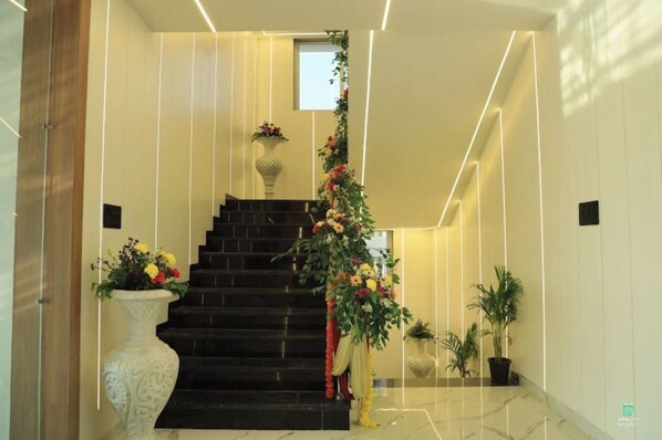 Una escalera moderna con acabado oscuro, flanqueada por jarrones decorativos y plantas en macetas.
