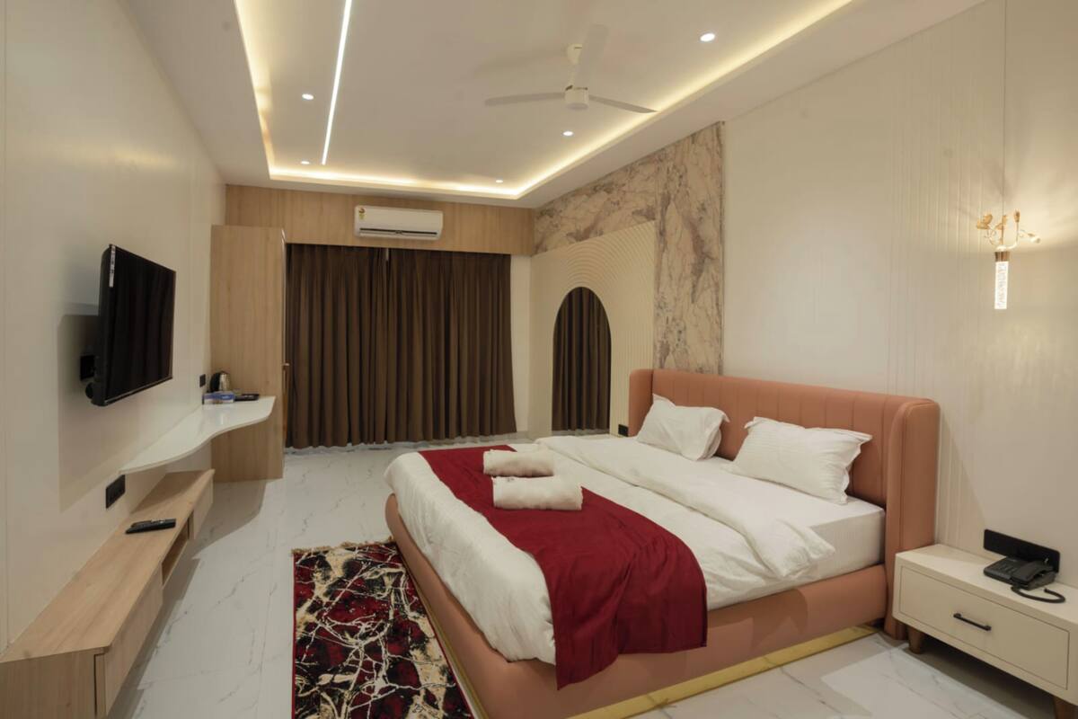 A modern bedroom with a bed, bedside table, and a TV mounted on the wall.