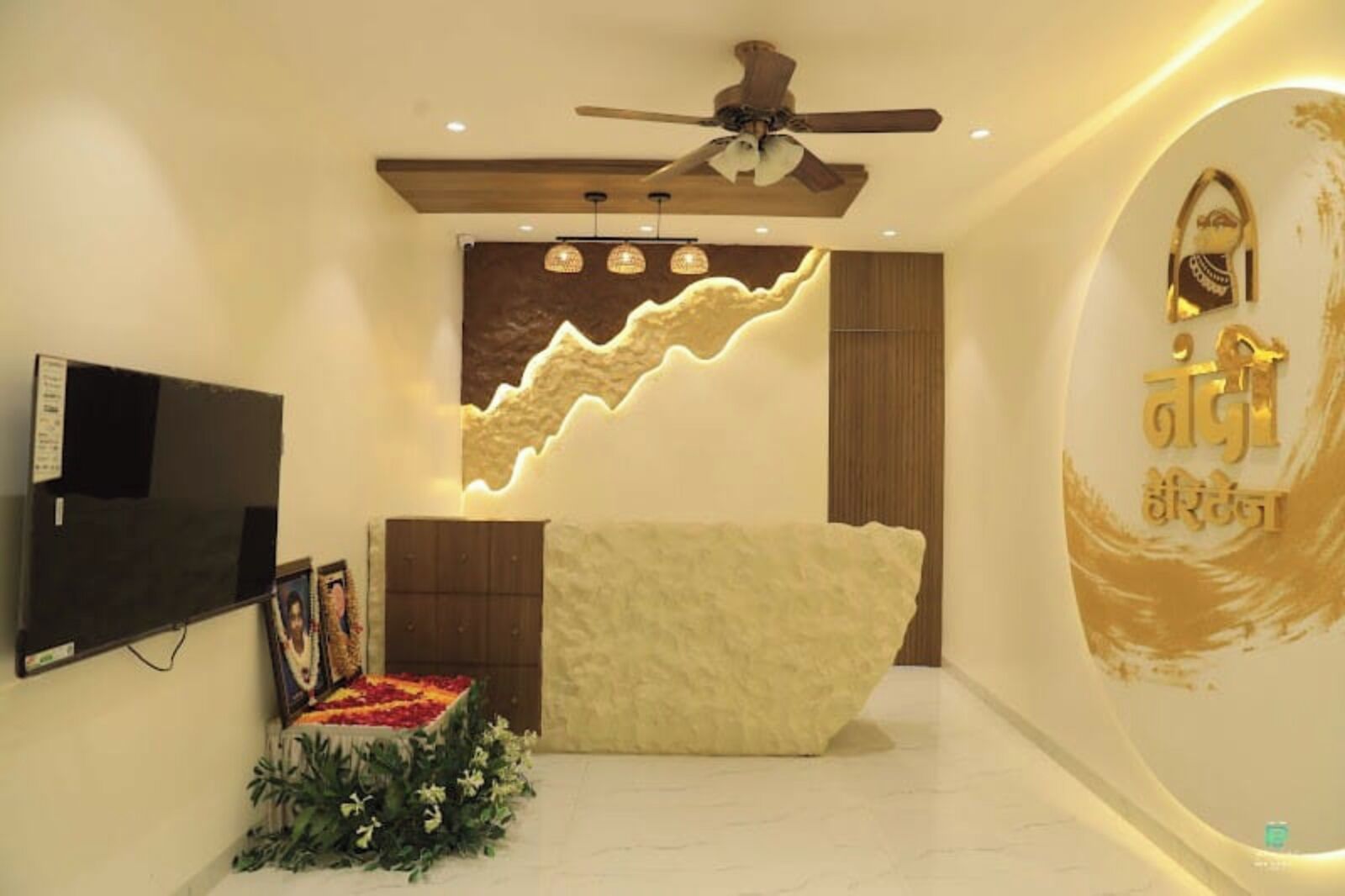 Una sala de estar moderna con un televisor de pantalla plana, un sofá, un muro decorativo y un ventilador de techo.