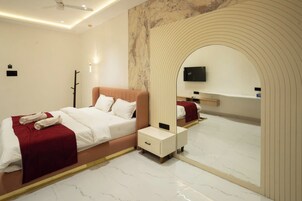 Una habitación de hotel moderna con una cama, una mesita de noche, un espejo y un televisor montado en la pared.