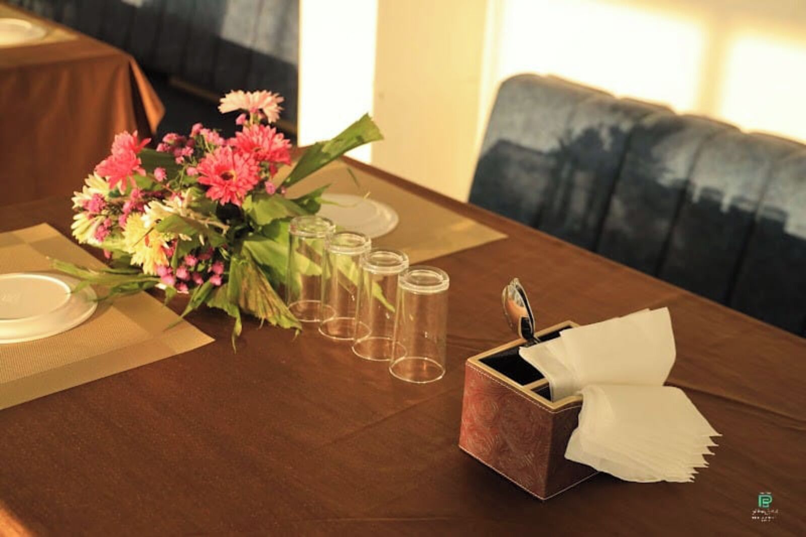 Una mesa de comedor con un centro de mesa floral, cristalería transparente y un portavelas.