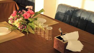 Una mesa de comedor con un centro de mesa floral, cristalería transparente y un portavelas.