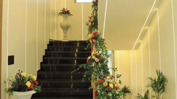 Eine Treppe mit einer Blumenkomposition, einer weißen Vase mit Blumen und einem Topfpflanzen.