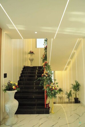 A staircase with a floral arrangement, a white vase with flowers, and a potted plant. - Nandi Heritage Pusad (Pusad)