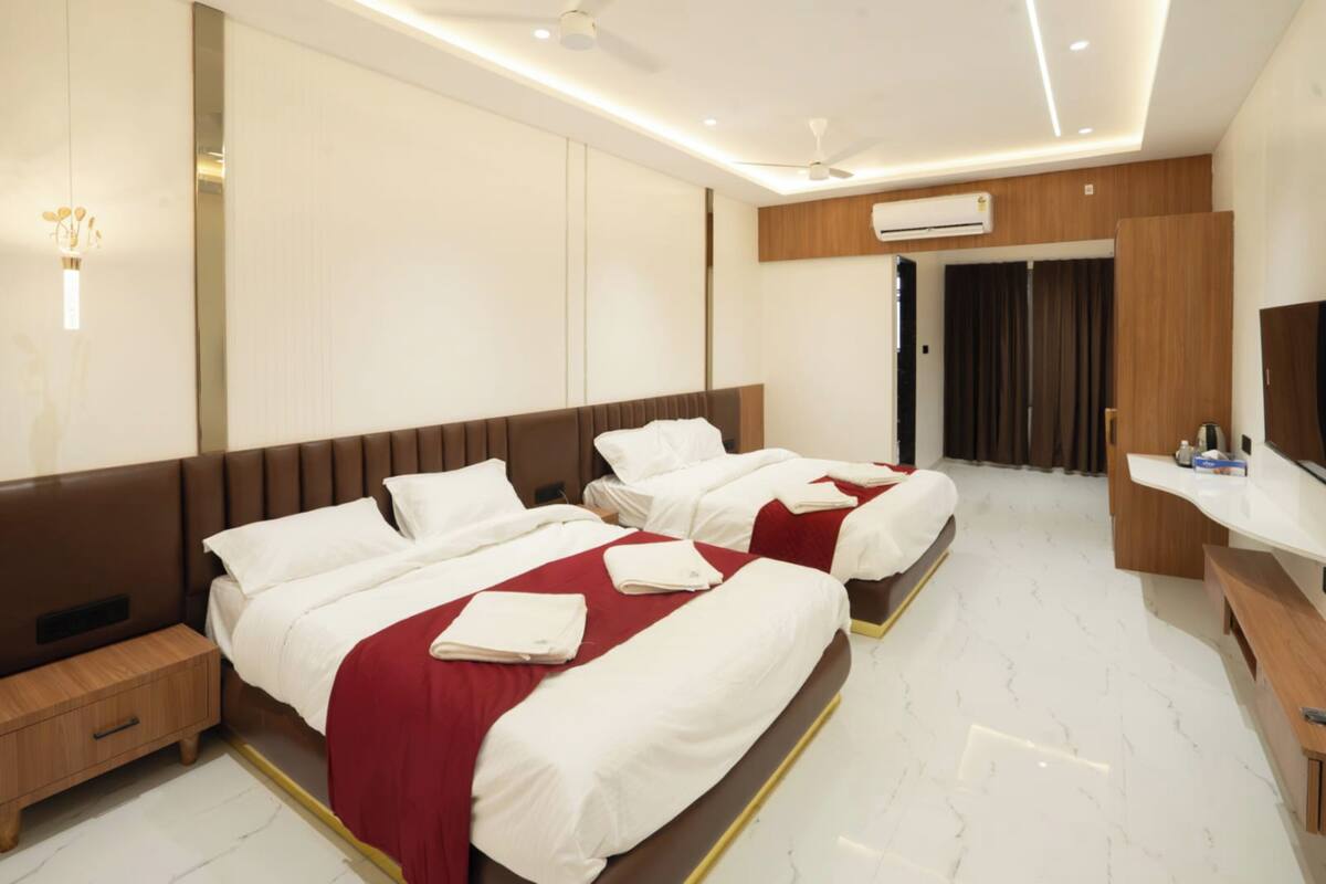 A hotel room with two beds, a desk, and a TV.