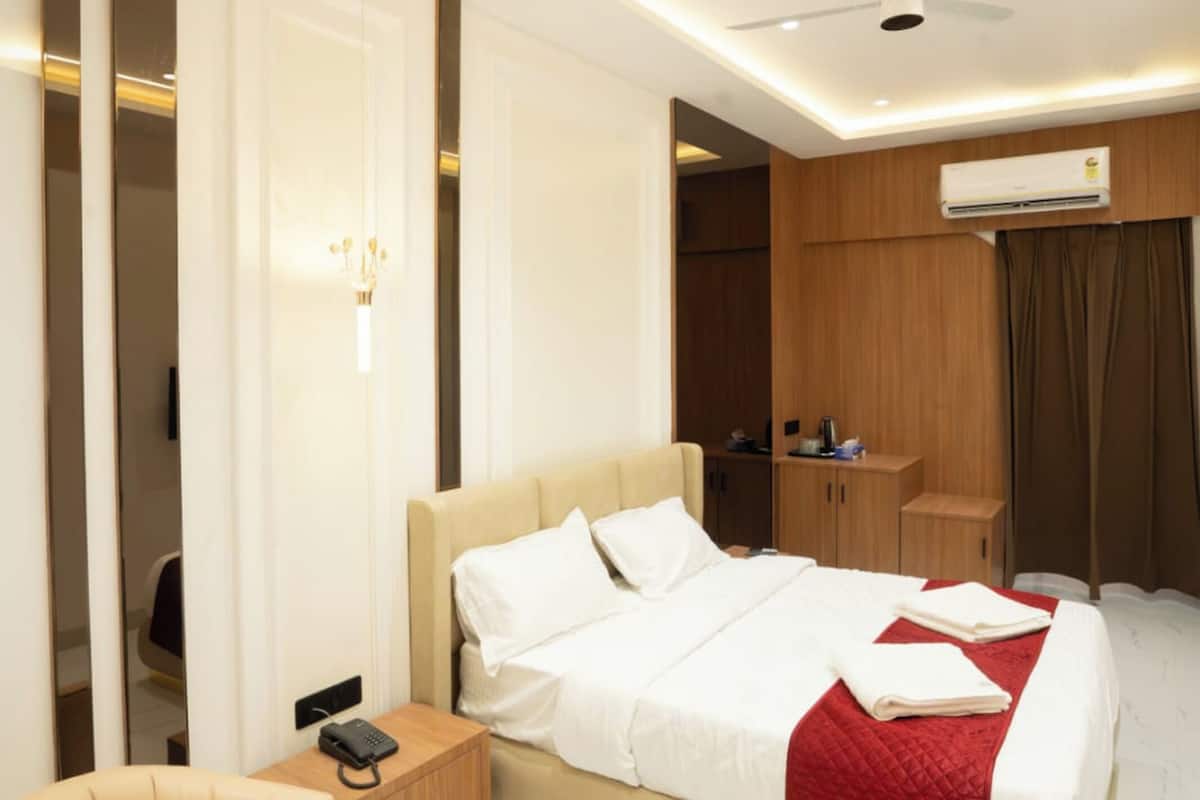 A modern bedroom with a large bed, a bedside table, a chair, and a ceiling fan.