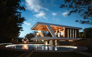 A modern house with a swimming pool, large windows, and a unique geometric design.