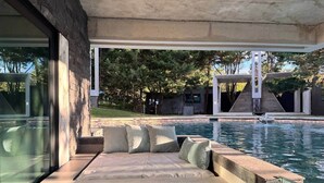 Ein moderner Poolbereich im Freien mit einer integrierten Sitzgelegenheit und Blick auf die umliegende Landschaft.
