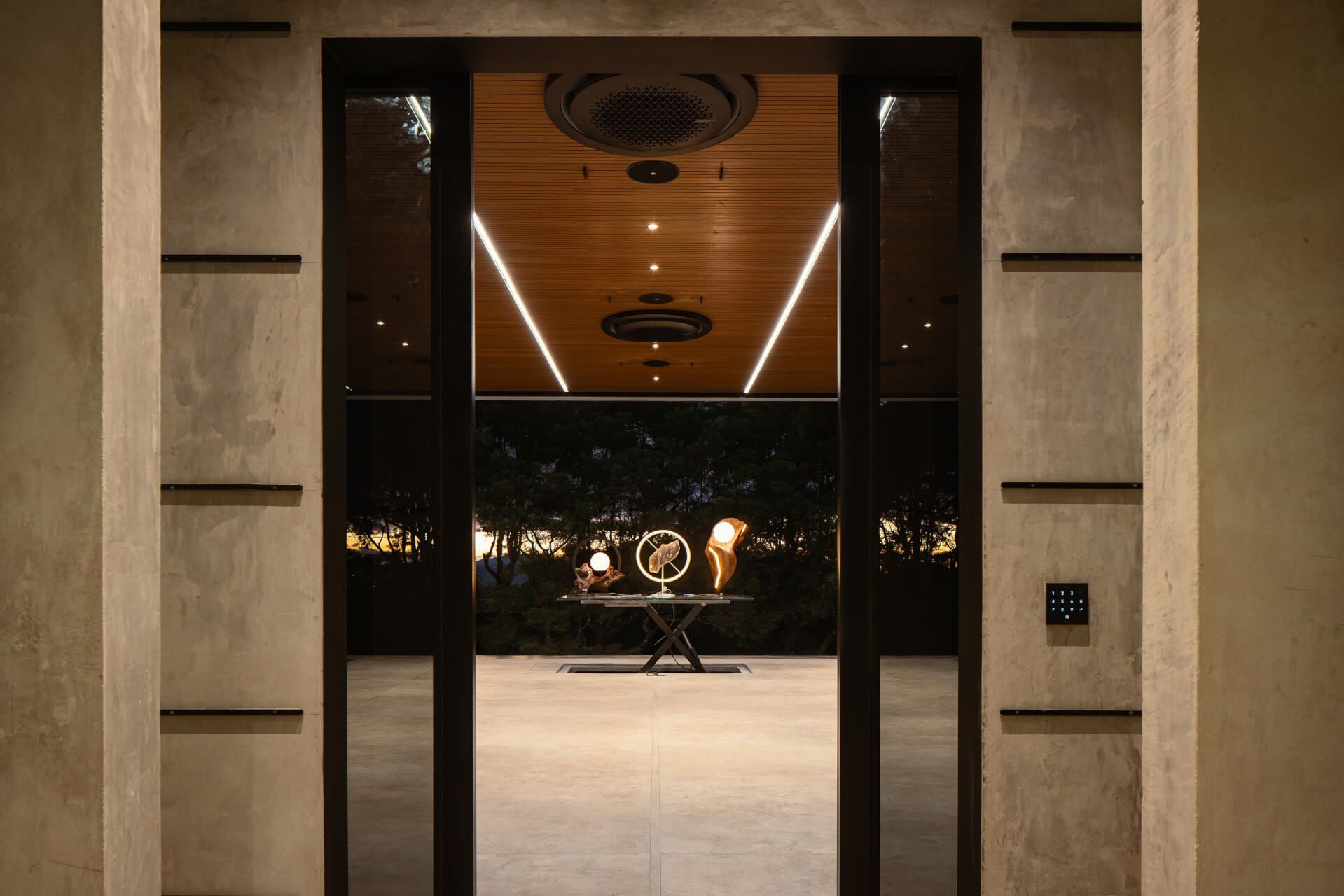 Een interieur met een modern design, met een centrale tafel met een uniek sculptuur, een plafond met ronde verlichtingsarmaturen en een zichtbare lift.