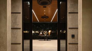 Een interieur met een modern design, met een centrale tafel met een uniek sculptuur, een plafond met ronde verlichtingsarmaturen en een zichtbare lift.